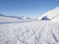 a man is riding his bike on a snowy path near mountains with snow and skis