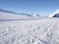 a man is riding his bike on a snowy path near mountains with snow and skis