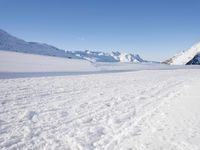 a man is riding his bike on a snowy path near mountains with snow and skis