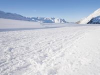 a man is riding his bike on a snowy path near mountains with snow and skis