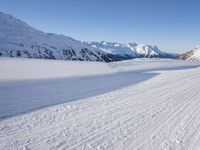 a man is riding his bike on a snowy path near mountains with snow and skis