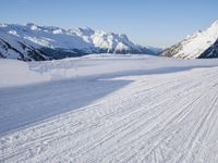 a man is riding his bike on a snowy path near mountains with snow and skis