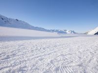 a man is riding his bike on a snowy path near mountains with snow and skis