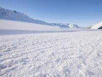 a man is riding his bike on a snowy path near mountains with snow and skis