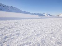 a man is riding his bike on a snowy path near mountains with snow and skis