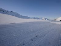 a man is riding his bike on a snowy path near mountains with snow and skis