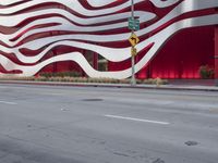 a man riding a bike in front of a building with red, white and silver stripes