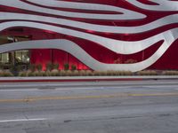 a man riding a bike in front of a building with red, white and silver stripes