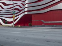 a man riding a bike in front of a building with red, white and silver stripes