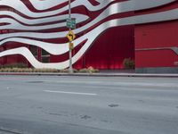 a man riding a bike in front of a building with red, white and silver stripes