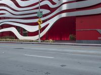 a man riding a bike in front of a building with red, white and silver stripes