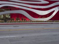 a man riding a bike in front of a building with red, white and silver stripes