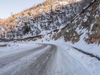 a man riding a horse in the snow past a rocky cliff on a country road