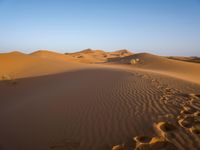 a man is riding a horse in the desert at sunset time near dunes that are covered with sand