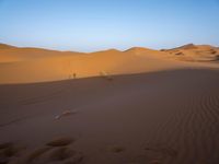 a man is riding a horse in the desert at sunset time near dunes that are covered with sand