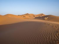 a man is riding a horse in the desert at sunset time near dunes that are covered with sand