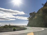 a man on his motorcycle rides along an empty road in the sunlight and it looks nice