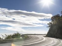 a man on his motorcycle rides along an empty road in the sunlight and it looks nice