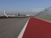 a man is riding his motorcycle on the track behind the fence and gate to the other side