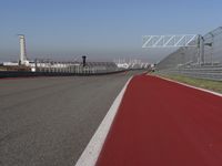 a man is riding his motorcycle on the track behind the fence and gate to the other side