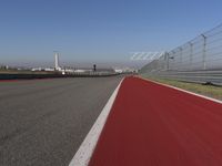 a man is riding his motorcycle on the track behind the fence and gate to the other side