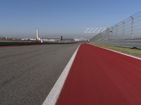 a man is riding his motorcycle on the track behind the fence and gate to the other side