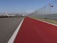 a man is riding his motorcycle on the track behind the fence and gate to the other side