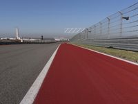 a man is riding his motorcycle on the track behind the fence and gate to the other side