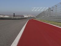 a man is riding his motorcycle on the track behind the fence and gate to the other side