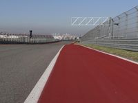 a man is riding his motorcycle on the track behind the fence and gate to the other side