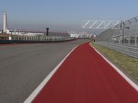 a man is riding his motorcycle on the track behind the fence and gate to the other side