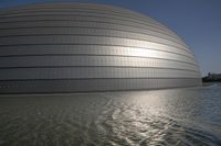 a person on a skateboard in front of a big building with a curved roof