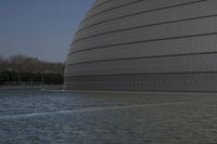 a person on a skateboard in front of a big building with a curved roof