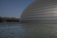 a person on a skateboard in front of a big building with a curved roof