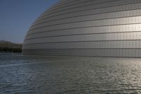 a person on a skateboard in front of a big building with a curved roof