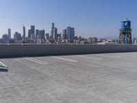 a man is sitting on top of a building with his skateboard in hand, and the view of a city is very wide