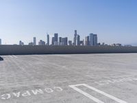 a man is sitting on top of a building with his skateboard in hand, and the view of a city is very wide