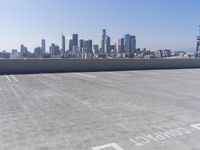 a man is sitting on top of a building with his skateboard in hand, and the view of a city is very wide