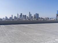 a man is sitting on top of a building with his skateboard in hand, and the view of a city is very wide