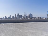 a man is sitting on top of a building with his skateboard in hand, and the view of a city is very wide