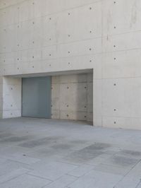a man on a skateboard stands outside of an empty building and looks out from a glass entrance