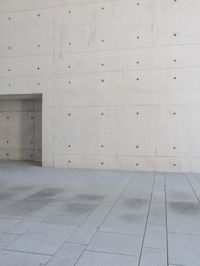 a man on a skateboard stands outside of an empty building and looks out from a glass entrance