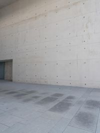 a man on a skateboard stands outside of an empty building and looks out from a glass entrance