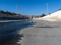 a man standing on the road with his skateboard in hand and water flowing from the street