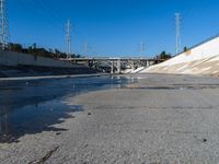 a man standing on the road with his skateboard in hand and water flowing from the street