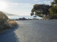 a man is riding his skateboard on the road near the water and mountains during a sunny day
