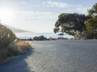 a man is riding his skateboard on the road near the water and mountains during a sunny day