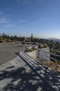 the man is on his skateboard over an elevated walkway with view of the city and park beyond