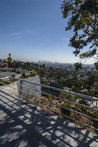 the man is on his skateboard over an elevated walkway with view of the city and park beyond