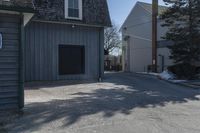 a man skates down the street in front of a building with a garage and an outdoor grill area